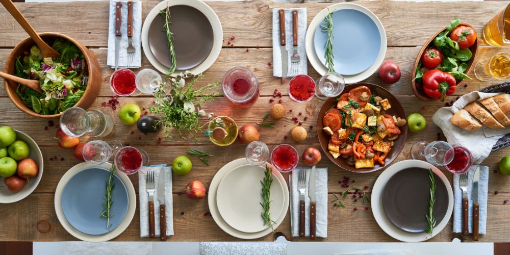 mesa llena de platos y cubiertos con cenas saludables