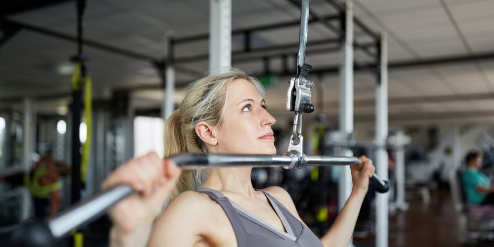 Mujer haciendo ejercicio con una máquina en el gimnasio sobre el pecho.