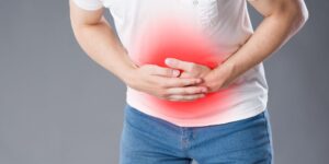 Hombre sujetándose la barriga con las dos manos con dolor.