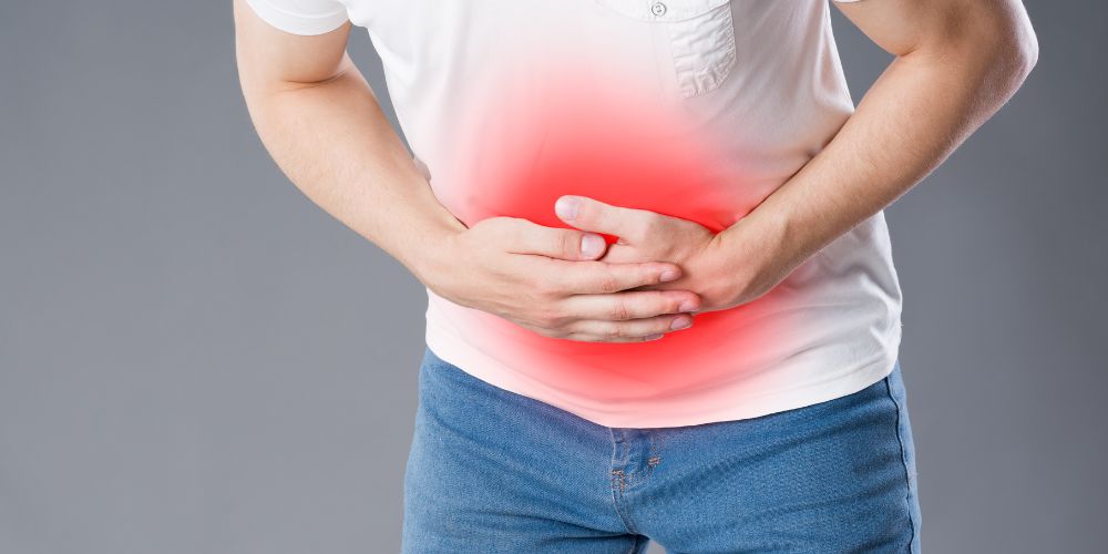 Hombre sujetándose la barriga con las dos manos con dolor.