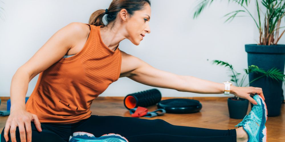 Mujer agarrándose una pierna estirada en casa.