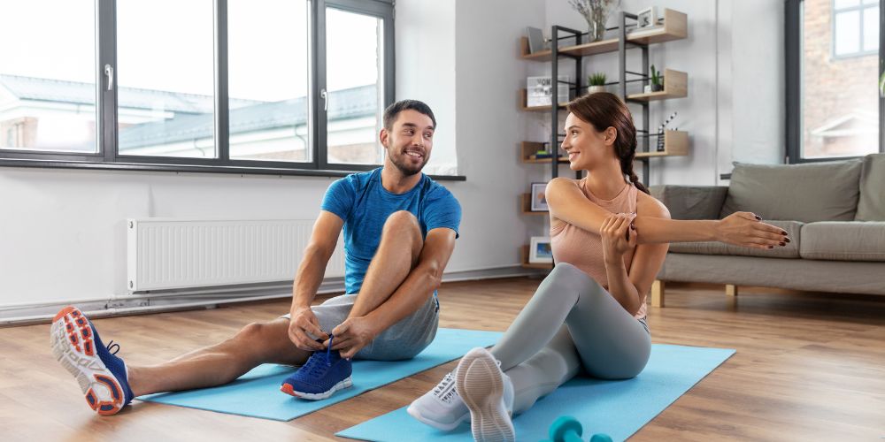 Hombre y mujer haciendo ejercicio en unas esterillas en casa. 