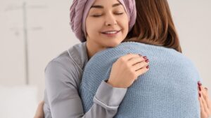 Mujer con pañuelo en la cabeza dando un abrazo a otra mujer.