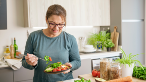 Señora comiendo un plato de verduras con alegría